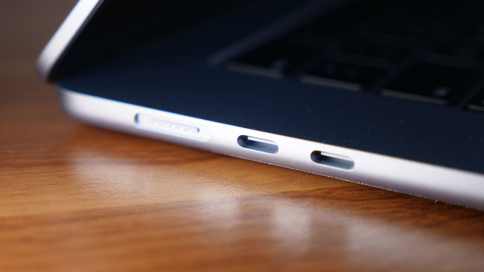 Close up photo of the left ports on a laptop, on top of a wooden surface.