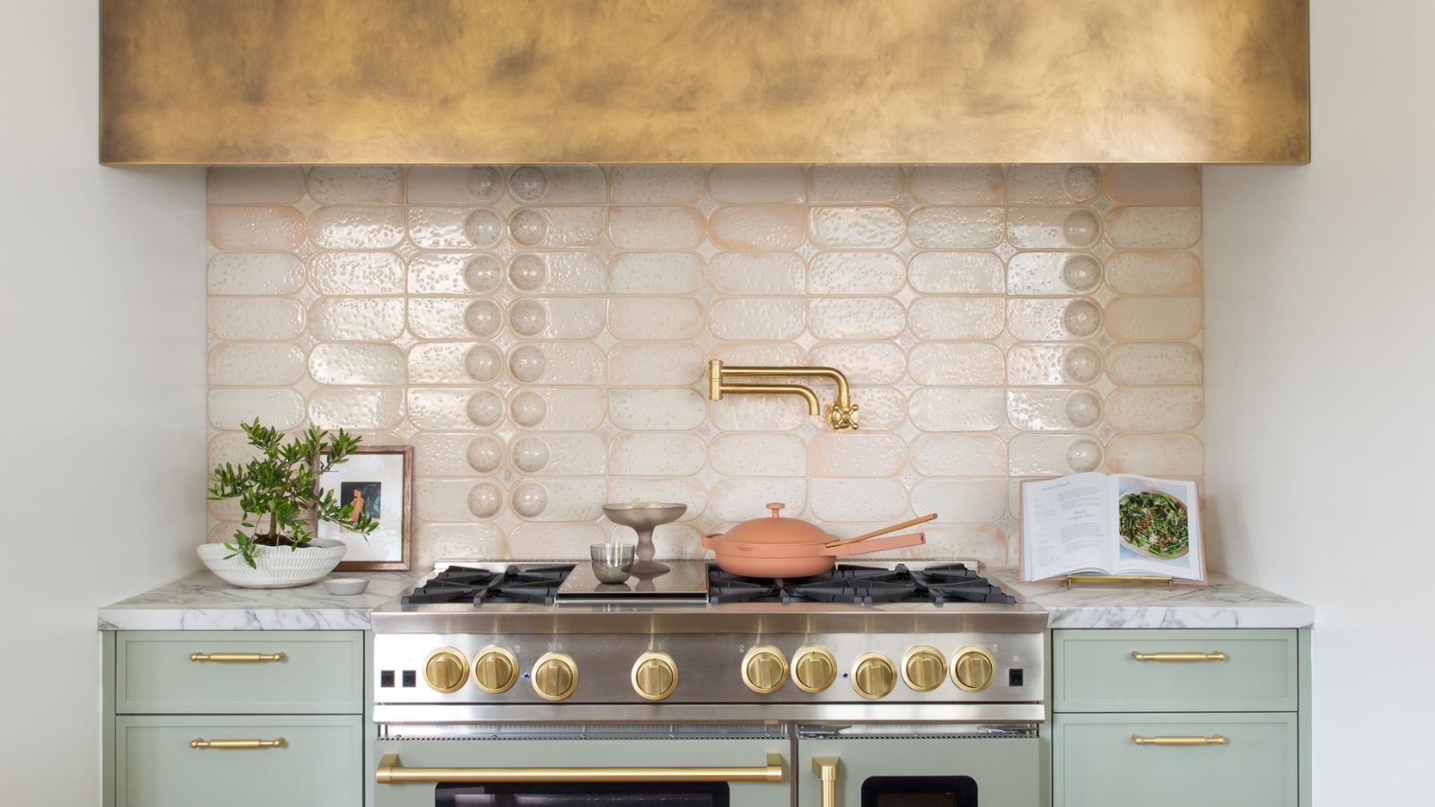 gold wall cabinet and extractor cover above pale green cabinets