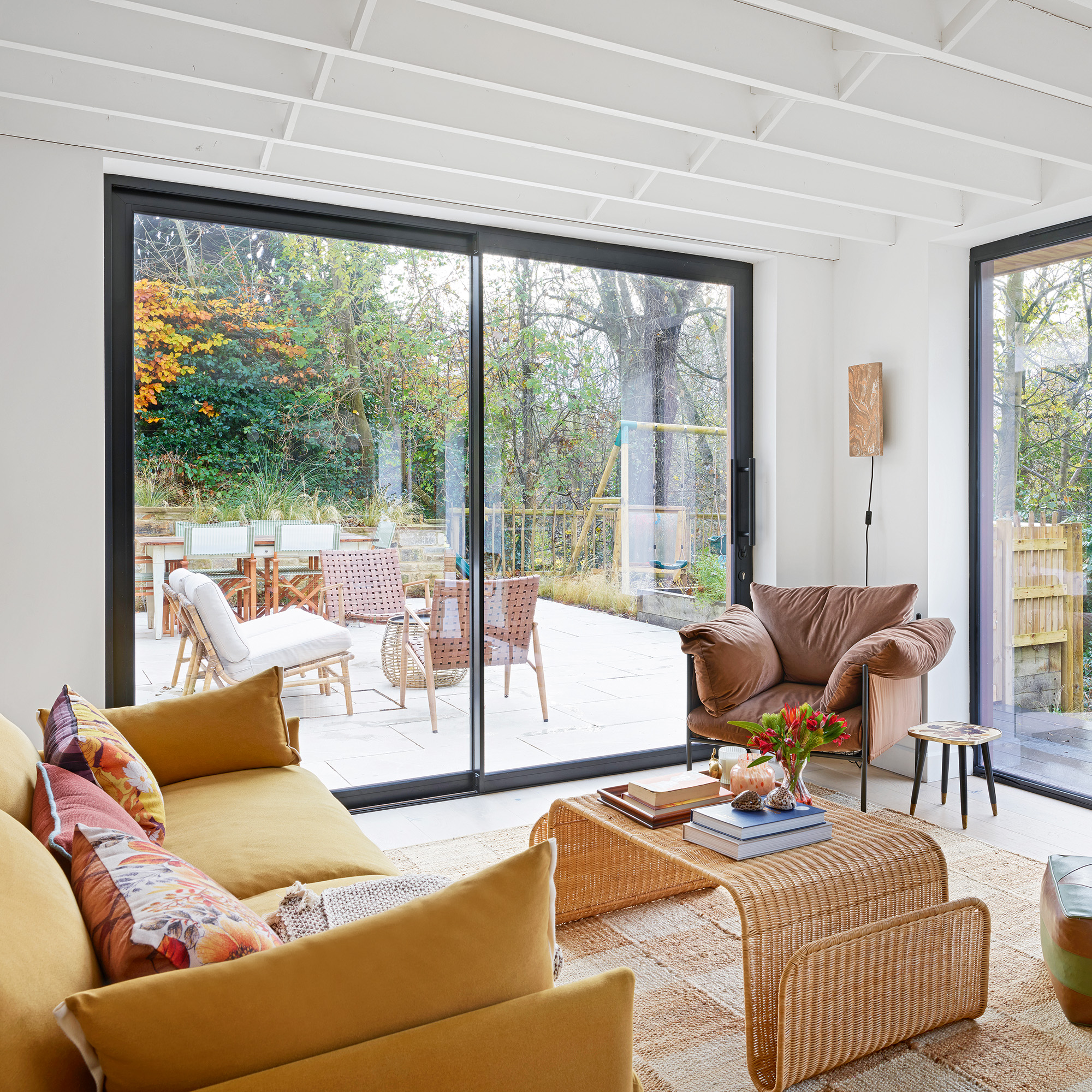 sliding glazed doors in living room with yellow sofa and brown armchair and rattan coffee table