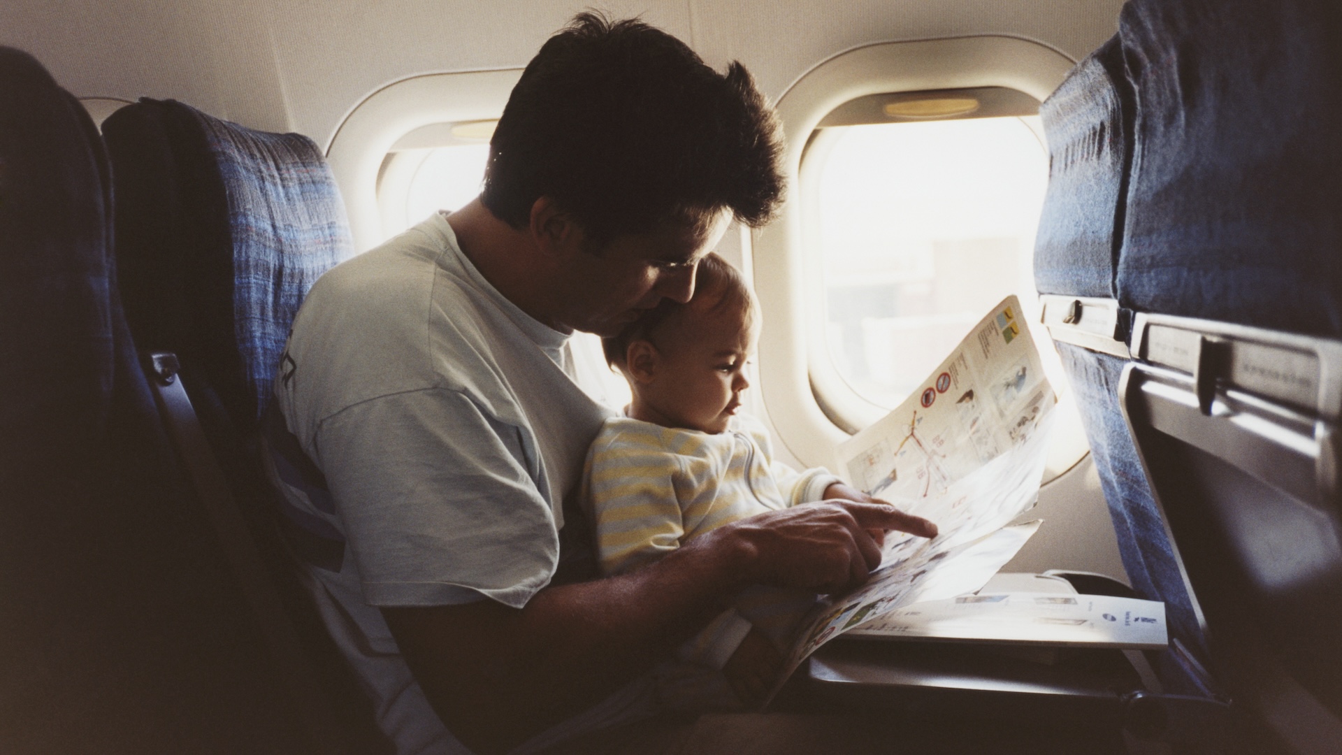 a father hold his infant son on an airplane
