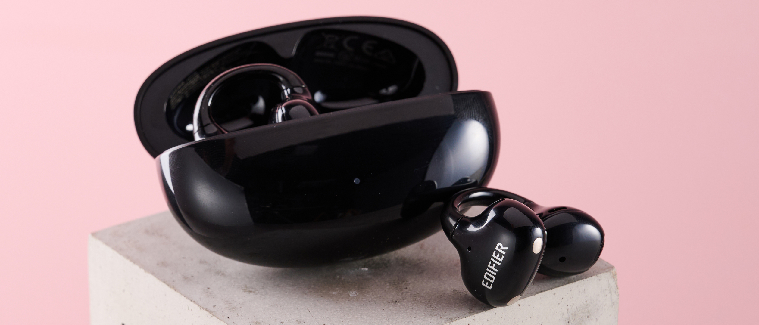 One of the Edifier LolliClip open ear headphones leaning against charging case