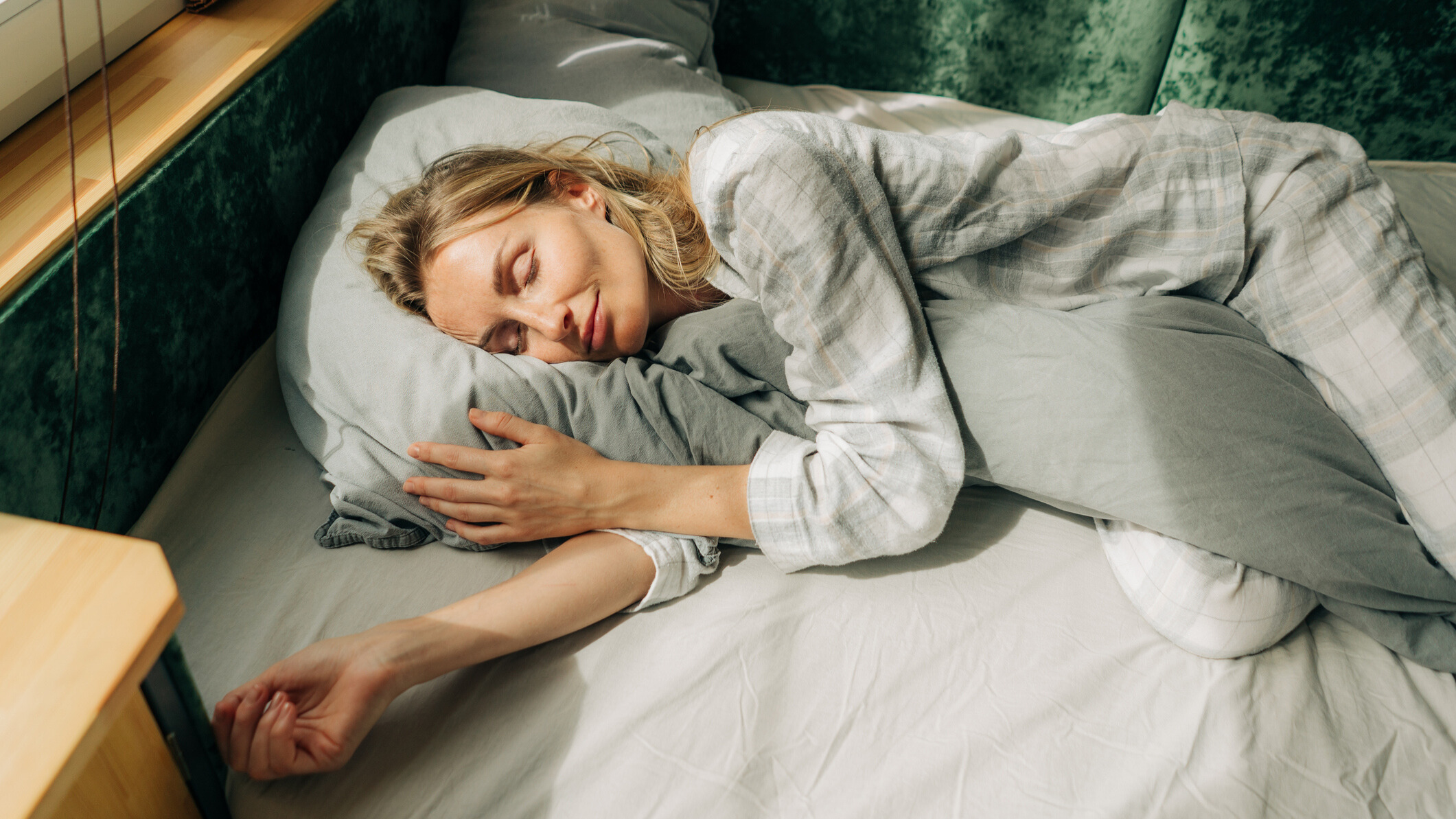 Woman sleeping next to a window in sunlight
