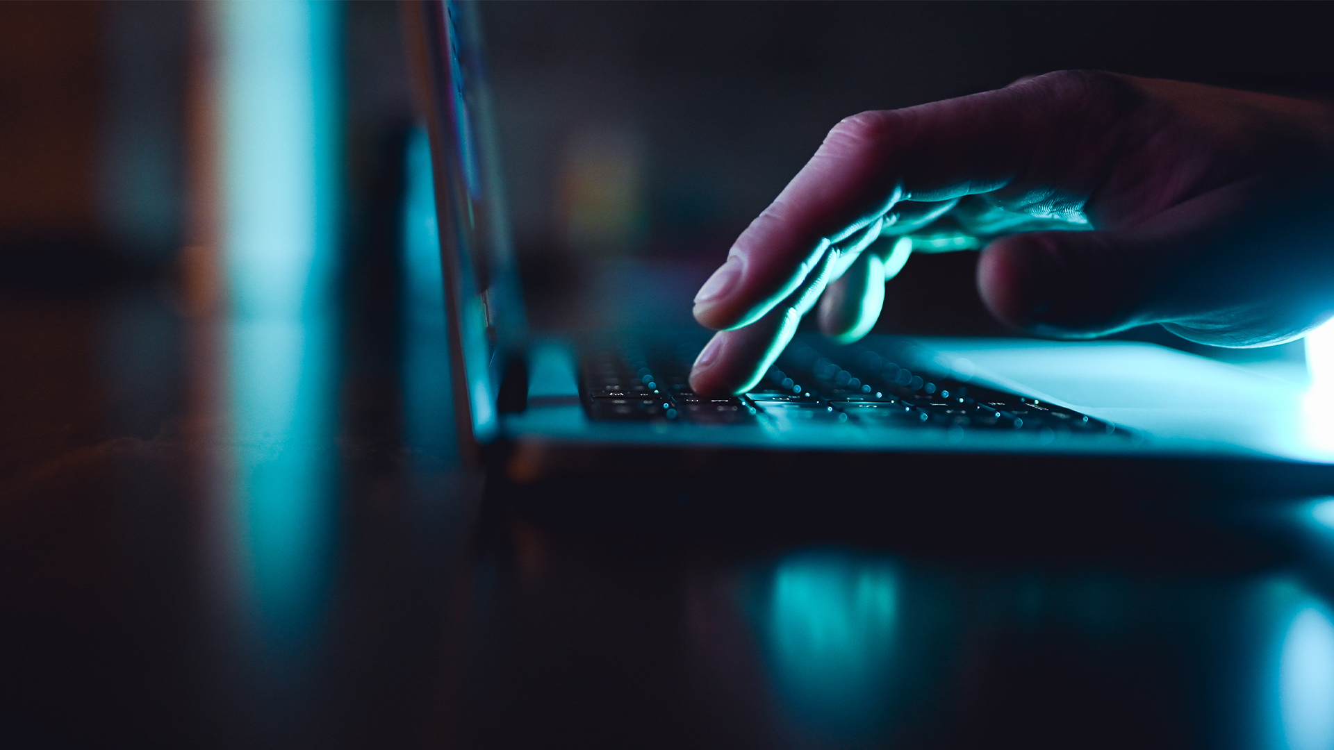 ClickFix social engineering technique concept image showing hand pressing a laptop keyboard button in low light.