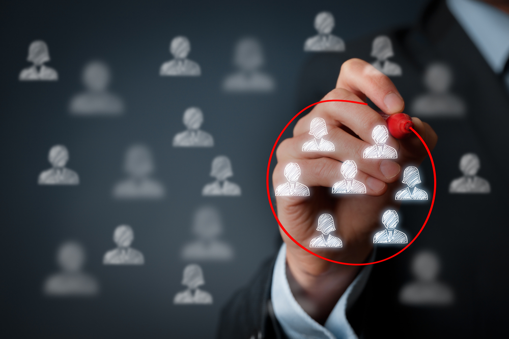 A businessman circling silhouettes with a red marker