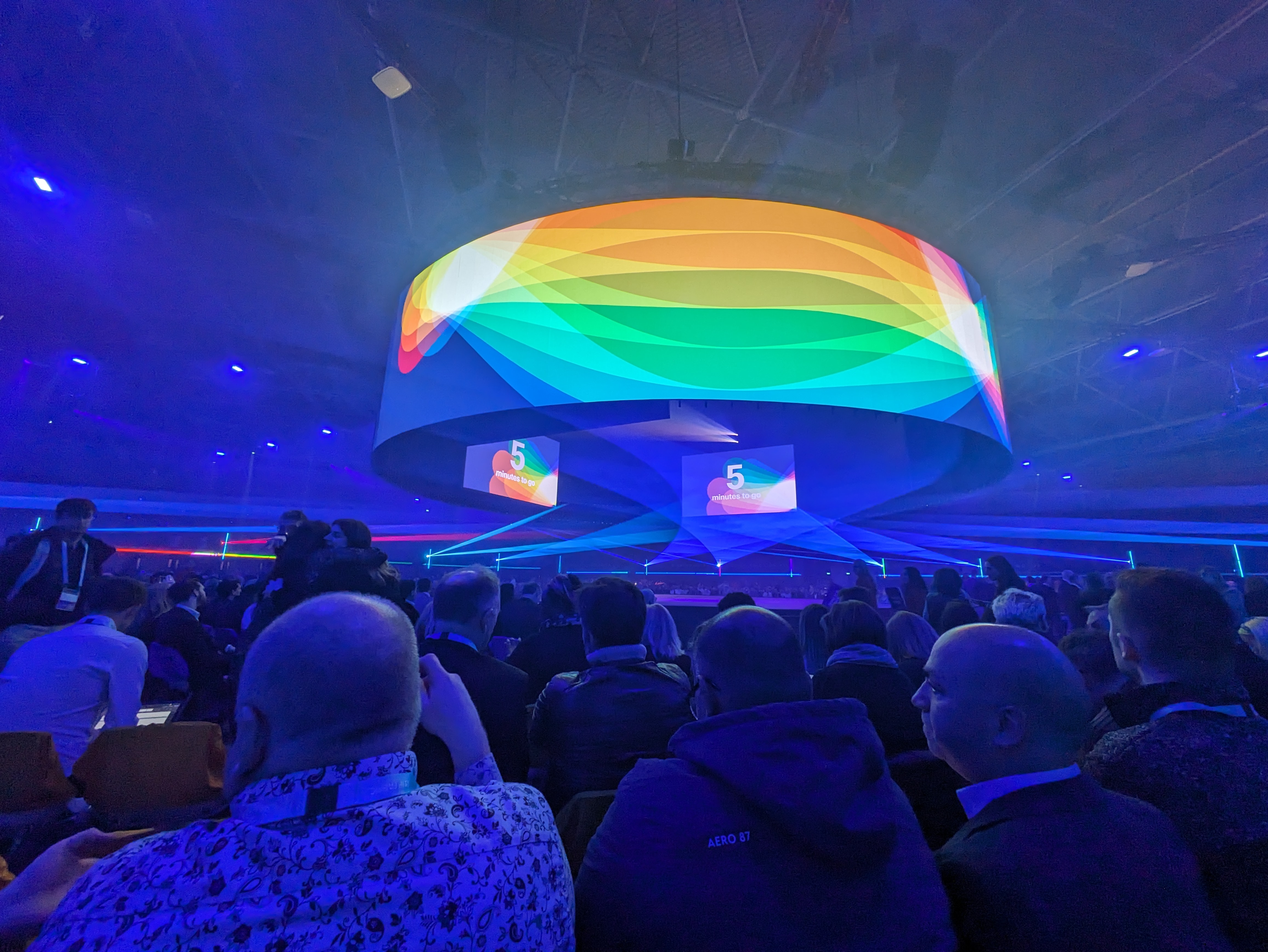 Graphic reading' 5 minutes to go' displayed on big screens in a keynote arena