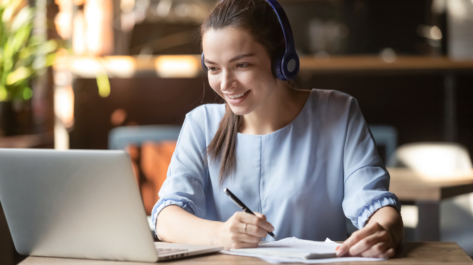 Bästa headset för videomöten: En kvinna sitter i ett videomöte med ett svart headset på sig.