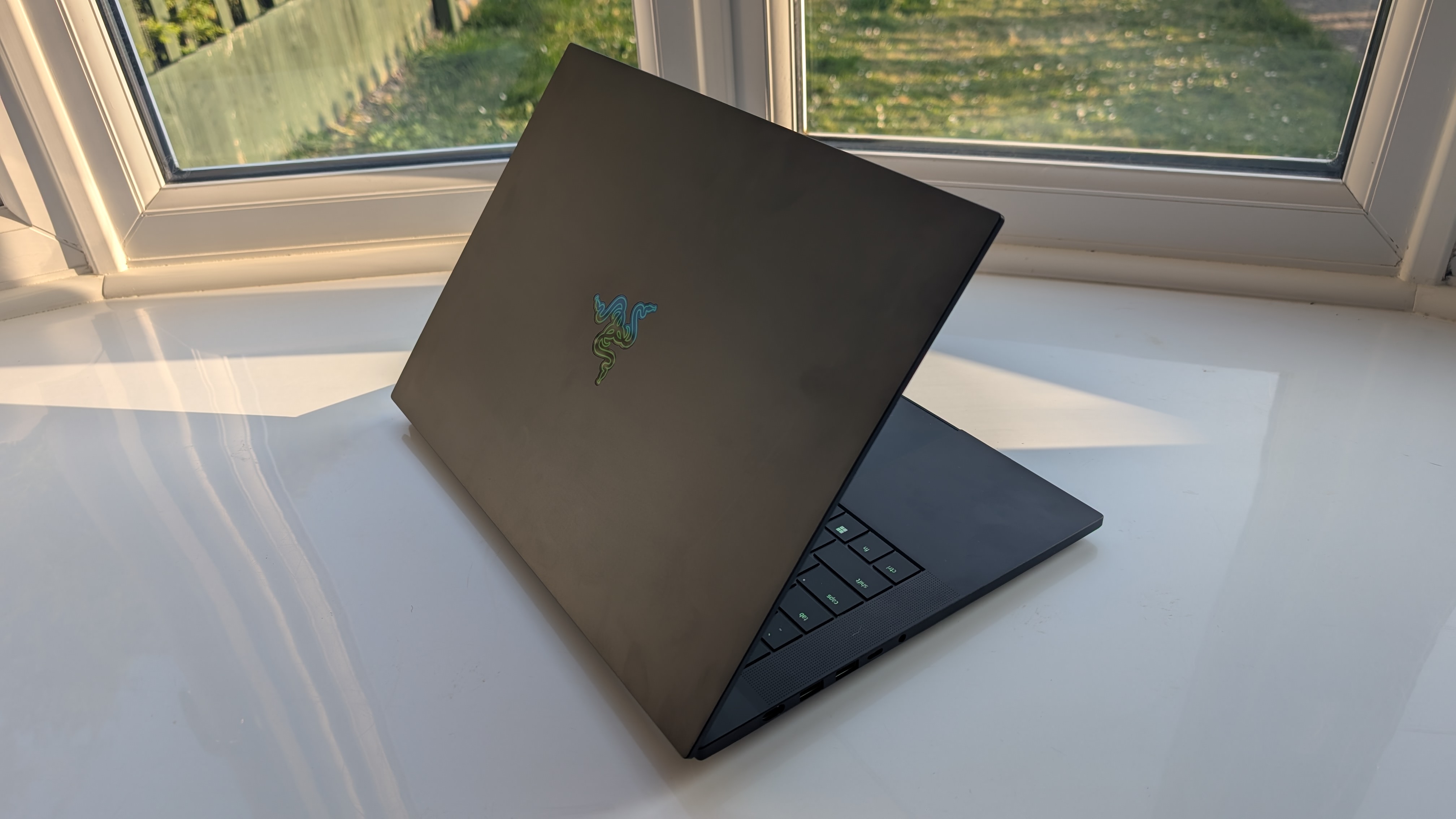 The Razer Blade 16 photographed for TechRadar on a white surface with plants in the background.