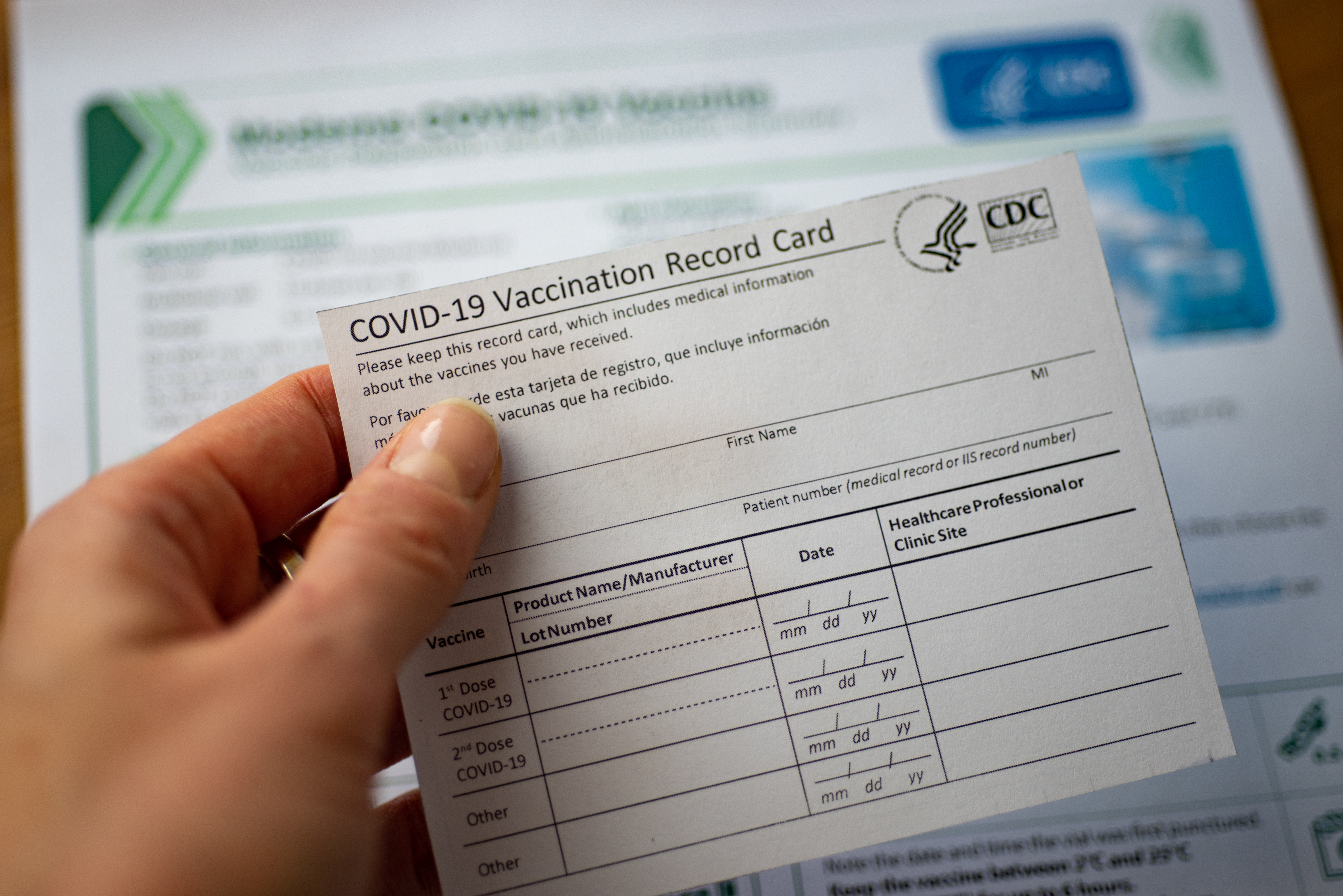 Woman's hand holding a COVID-19 vaccination card