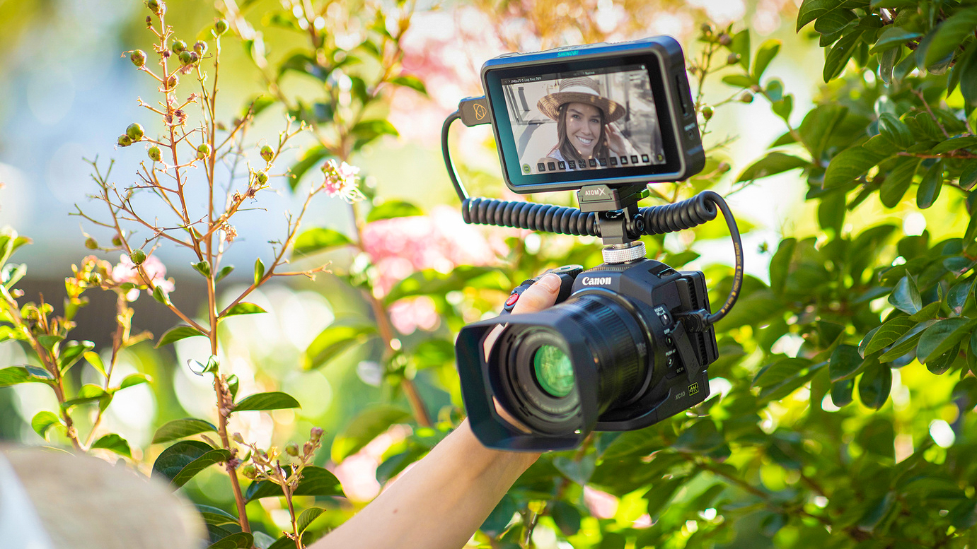Atomos field monitor on a Canon cinema camera being held outdoors